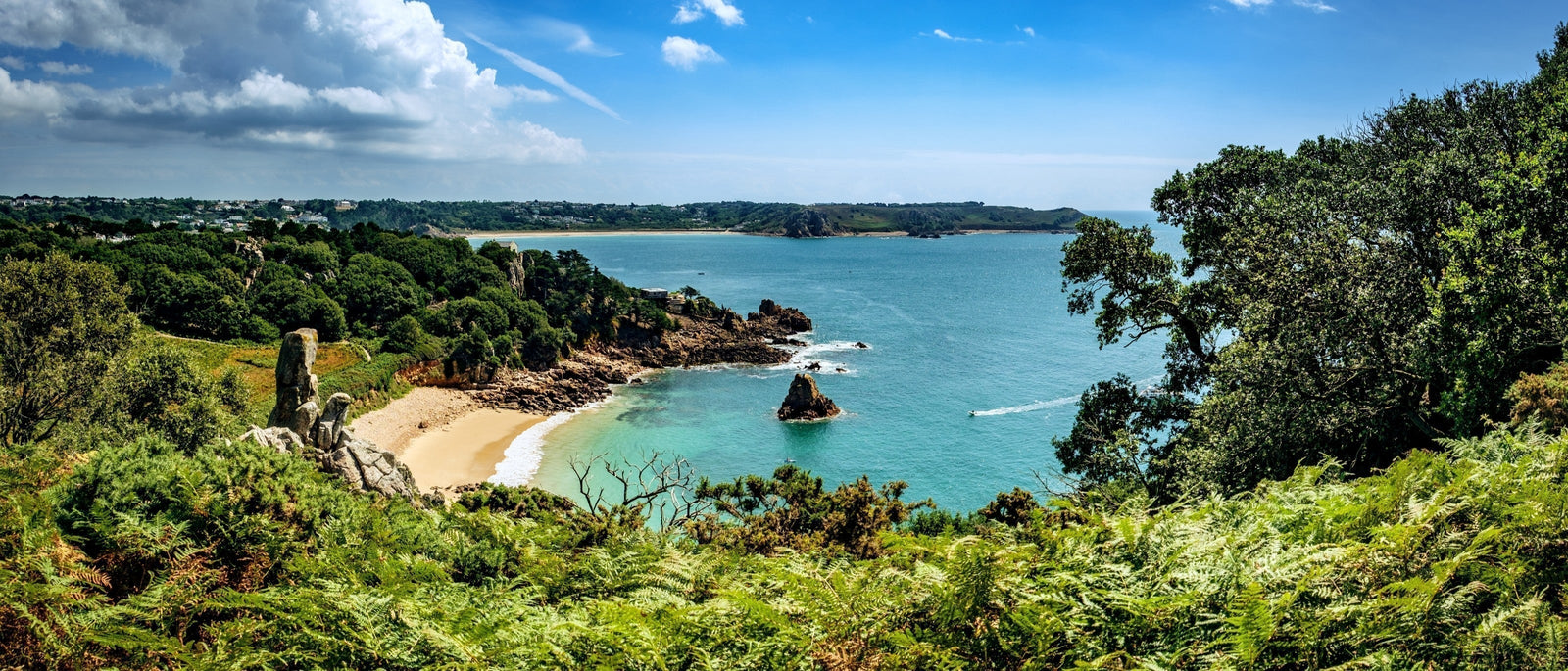 The golden sands, azure sea and lush greenery of Beauport Bay, St. Aubin, Jersey, Channel Islands.