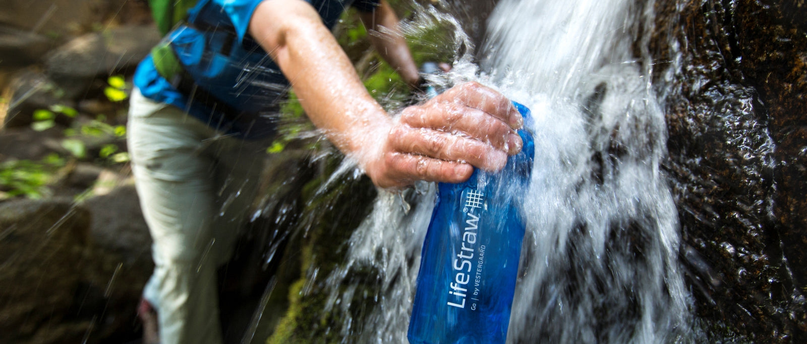 Hand filling a LifeStraw Go filter bottle from a cascading waterfall. Wild water is everywhere in the hills – the trick is knowing what's in it.
