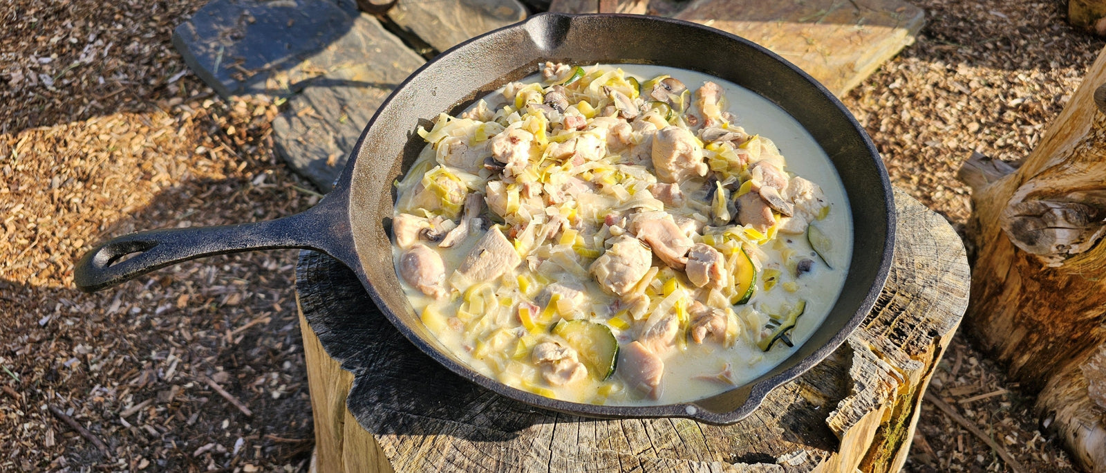 Poulet Breton chicken in white wine and cream sauce cooked on the campfire in a cast iron skillet