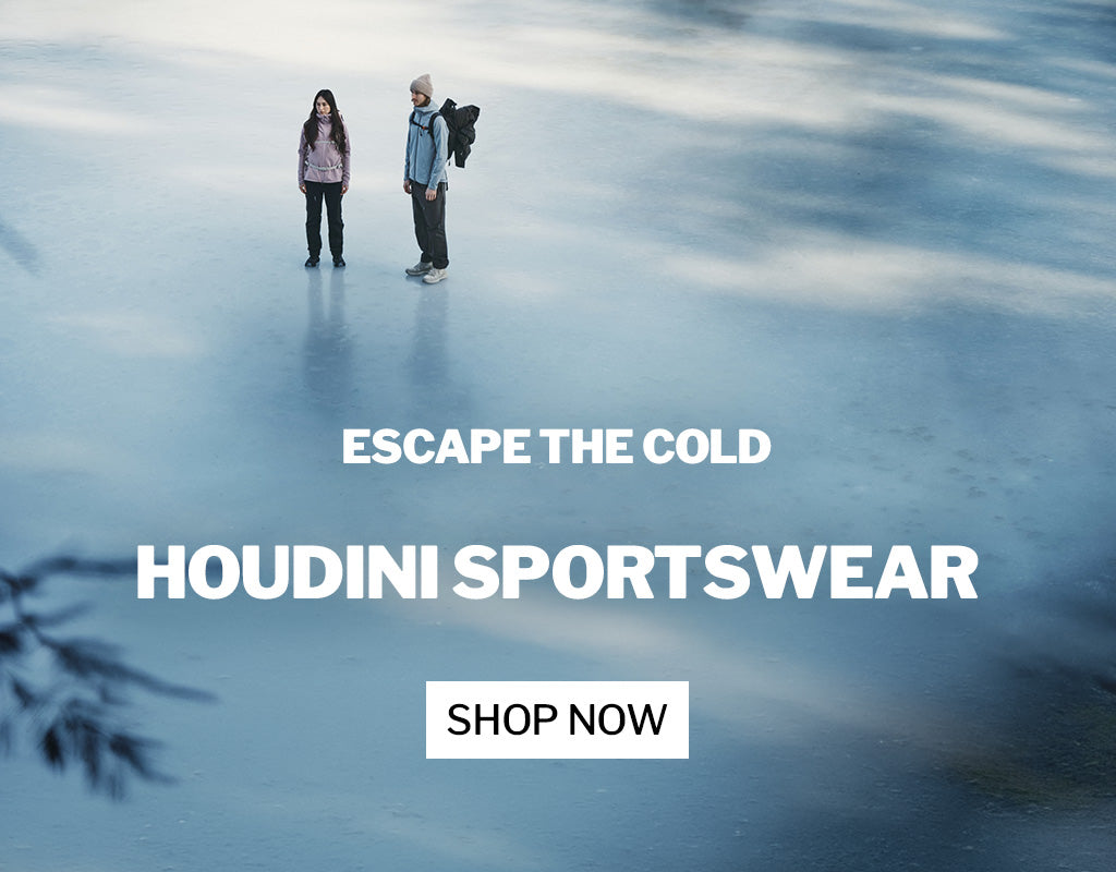 Two people standing on a frozen lake wearing winter gear with 'Escape the Cold Houdini Sportswear' text overlay